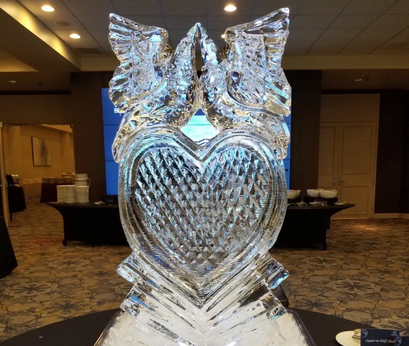 Ice sculpture of two doves above a carved heart at an event